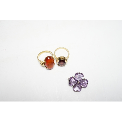 956 - A 333 yellow metal and amber set ring, a 585 and gem set ring and an amethyst and seed pearl set whi... 
