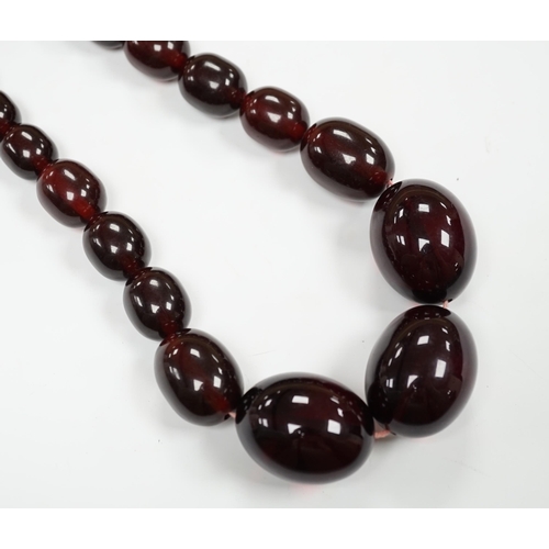 980 - A single strand graduated simulated cherry amber bead necklace, 68cm, gross weight 151 grams.