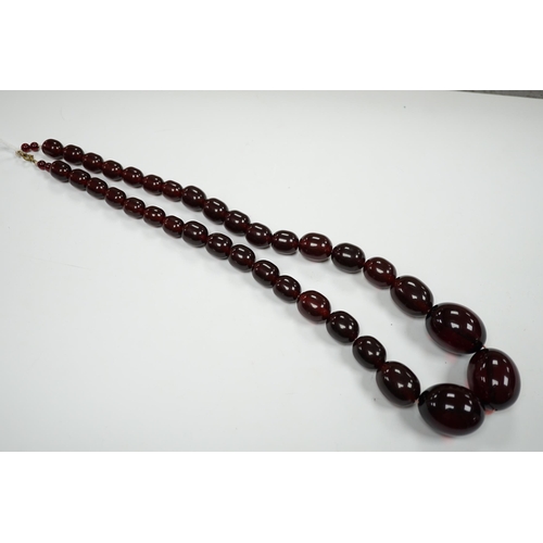 980 - A single strand graduated simulated cherry amber bead necklace, 68cm, gross weight 151 grams.