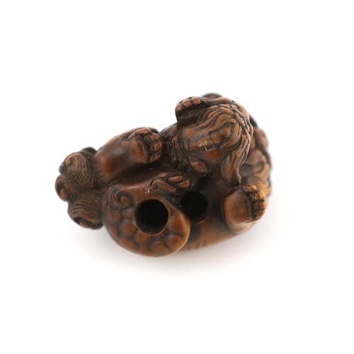 148 - * * A Japanese carved wood netsuke of a recumbent Shi-Shi, signed Toyomasa?, late 18th century, with... 