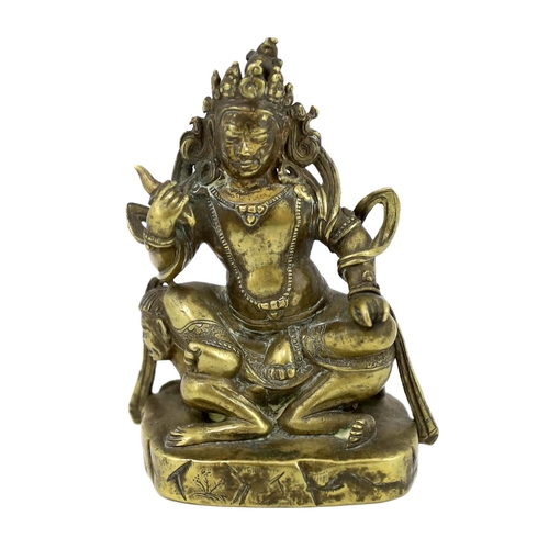 243 - * * A Tibetan gilt bronze figure of a deity, 17th century, holding a purba in his right hand, seated... 