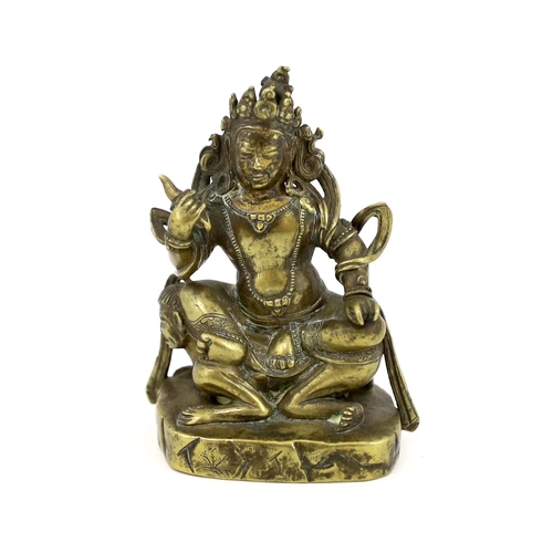 243 - * * A Tibetan gilt bronze figure of a deity, 17th century, holding a purba in his right hand, seated... 