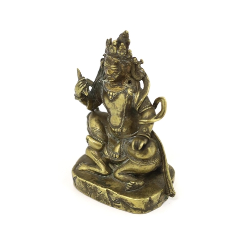 243 - * * A Tibetan gilt bronze figure of a deity, 17th century, holding a purba in his right hand, seated... 