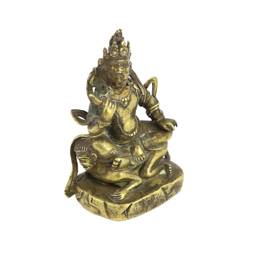 243 - * * A Tibetan gilt bronze figure of a deity, 17th century, holding a purba in his right hand, seated... 