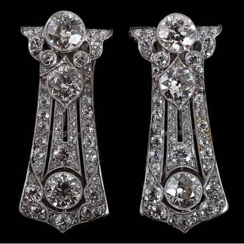 621 - A pair of Art Deco white gold and round cut millegrain set diamond cluster clip brooches, of taperin... 