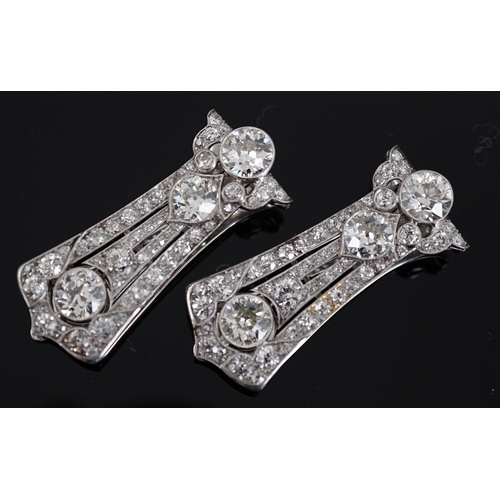 621 - A pair of Art Deco white gold and round cut millegrain set diamond cluster clip brooches, of taperin... 