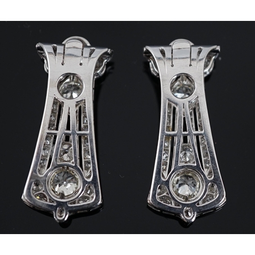 621 - A pair of Art Deco white gold and round cut millegrain set diamond cluster clip brooches, of taperin... 