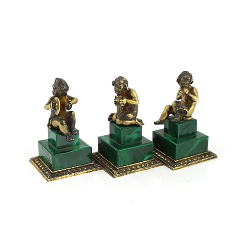 74 - A set of three Italian silver gilt figures of musical putti, each seated upon a stepped malachite ba... 