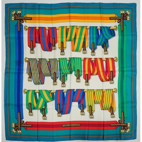 1045 - A Hermès Les Sangles silk scarf, with belt and buckle pattern in hues of white, red, blue, green, an... 