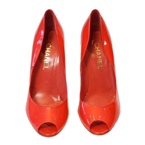 1057 - A pair of Chanel lady's metallic coral peep toe patent leather heels, with gold tone CC detail to th... 