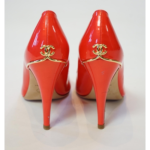 1057 - A pair of Chanel lady's metallic coral peep toe patent leather heels, with gold tone CC detail to th... 