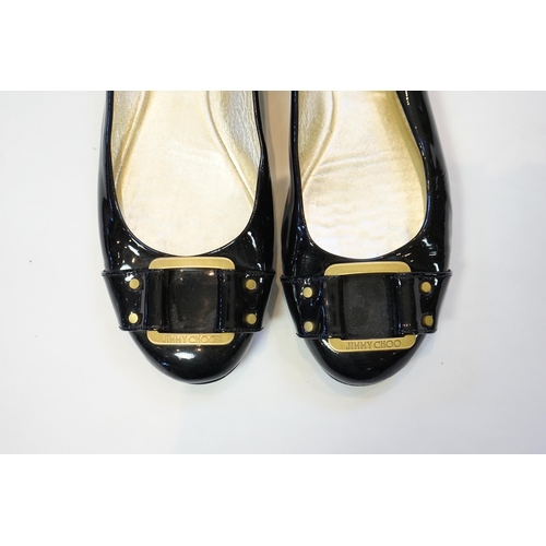 1071 - A pair of Jimmy Choo lady's black patent leather pumps with gold buckle, with rubber sole and dust b... 