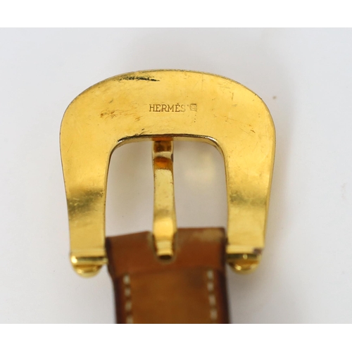 1101 - A Hermès lady's tan leather belt, with gold tone buckle and white stitching, size XS/Small