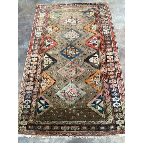 1180 - A Caucasian rug with geometric motifs on brown ground, 200 x 122cm