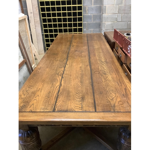 121 - A very large 17th century style oak refectory dining table, with cleated three plank top on carved b... 