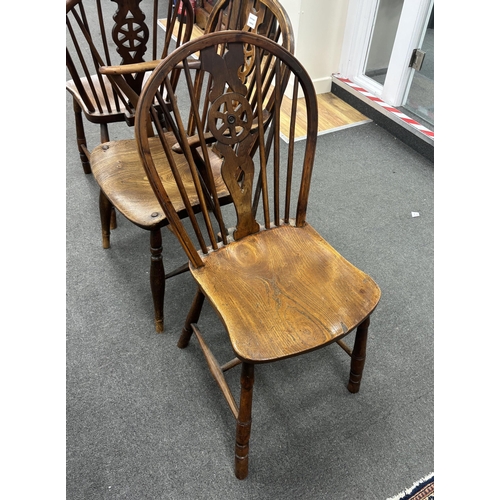 1170 - A set of three mid 19th century elm and ash wheel back dining chairs, one with arms