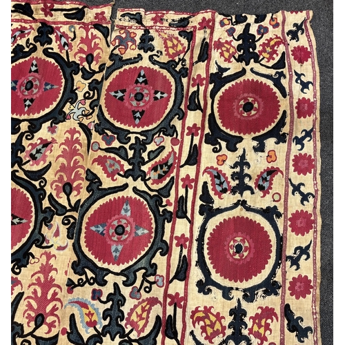 1332 - An 19th century Uzbek Suzani embroidered wall hanging, in two pieces, the main hanging sewn together... 