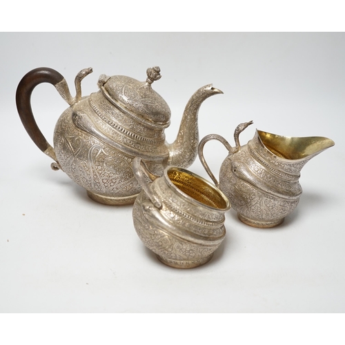 852 - A 20th century Indian three piece embossed white metal tea set, with boteh and cobra decoration, gro... 