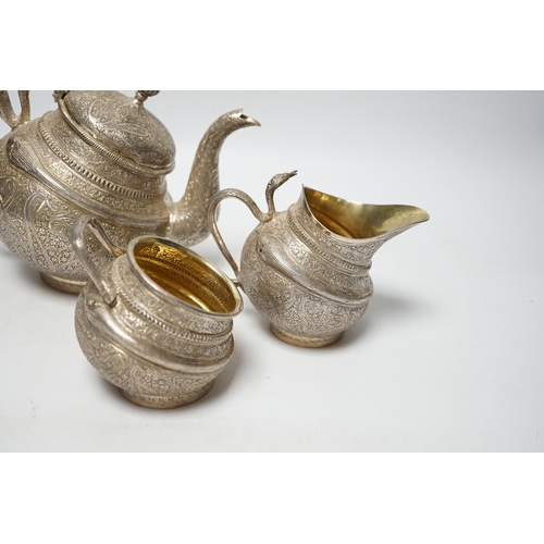 852 - A 20th century Indian three piece embossed white metal tea set, with boteh and cobra decoration, gro... 