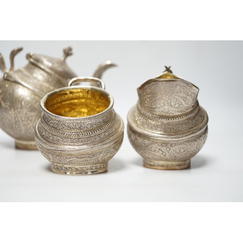 852 - A 20th century Indian three piece embossed white metal tea set, with boteh and cobra decoration, gro... 