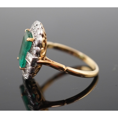 909 - An Art Deco style gold, emerald and diamond set oval cluster ring, the central emerald measuring app... 