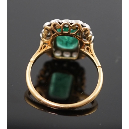 909 - An Art Deco style gold, emerald and diamond set oval cluster ring, the central emerald measuring app... 