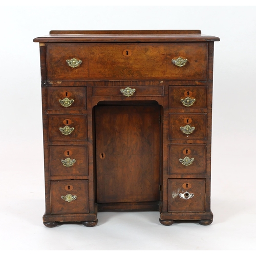 132 - An early 18th century walnut kneehole secretaire desk, with quarter veneered top and fall front draw... 