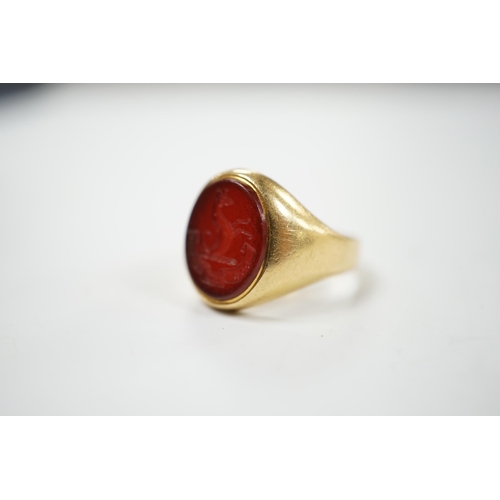 905 - An 18ct and oval intaglio carnelian set signet ring, carved with family crest and motto, size K, gro... 