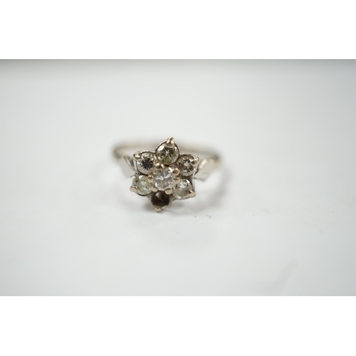 910 - An 18ct white metal and seven stone diamond cluster set flower head ring (one stone missing), size K... 