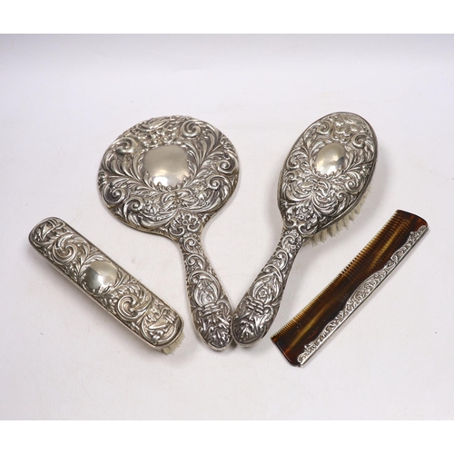 842 - A modern repousse silver mounted hand mirror, two brushes and a comb.