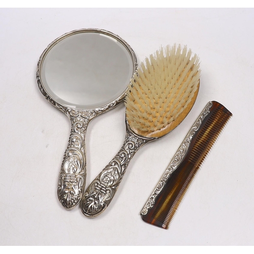 842 - A modern repousse silver mounted hand mirror, two brushes and a comb.