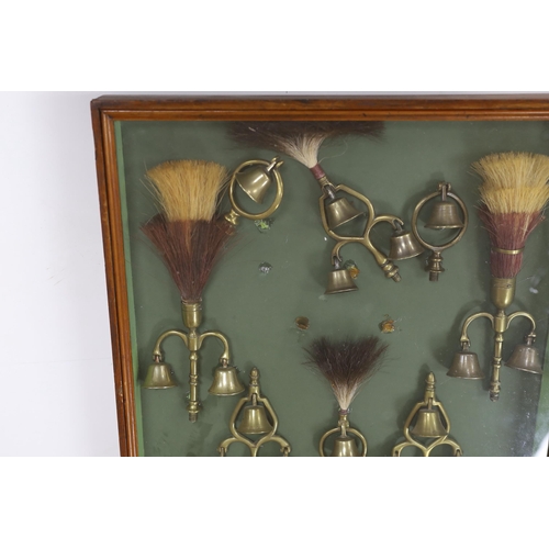 1379 - A collection of Victorian horse brass bell terrets, housed in a display case, 46cm high