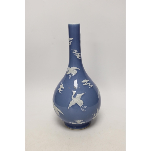 1409 - A Chinese blue bottle vase decorated in relief with cranes, on stand, 32cm high overall