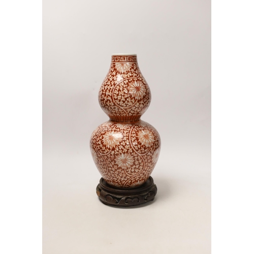 1412 - A Chinese iron-red double-gourd vase on hardwood stand, 29cm high