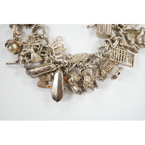 1936 - A 1970's silver charm bracelet, hung with assorted charms including birdcage, abacus, piglet, etc. a... 