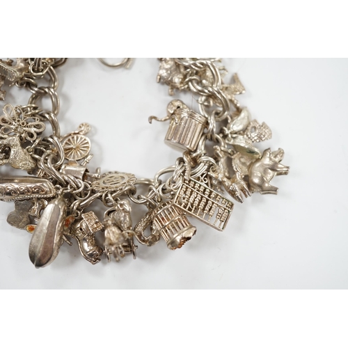 1936 - A 1970's silver charm bracelet, hung with assorted charms including birdcage, abacus, piglet, etc. a... 