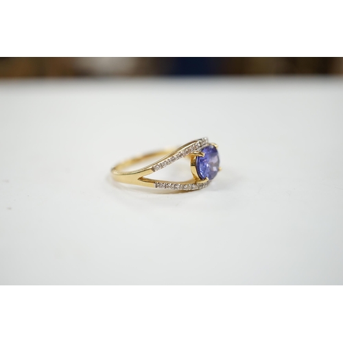 1938 - A modern 18ct gold and singe stone oval cut tanzanite ring, with diamond chip set borders, size N, g... 