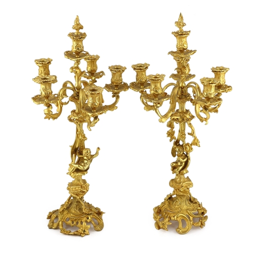 32 - A pair of Victorian style ormolu six light candelabra with rococo scroll extinguishers, scrolling br... 