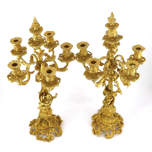 32 - A pair of Victorian style ormolu six light candelabra with rococo scroll extinguishers, scrolling br... 