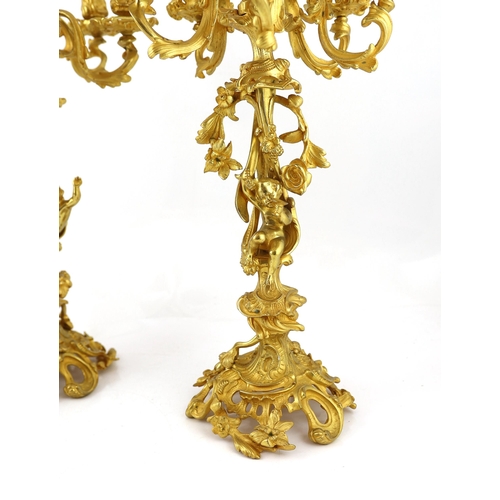 32 - A pair of Victorian style ormolu six light candelabra with rococo scroll extinguishers, scrolling br... 