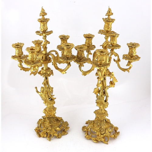 32 - A pair of Victorian style ormolu six light candelabra with rococo scroll extinguishers, scrolling br... 