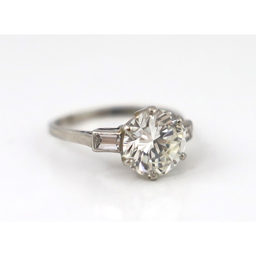 507 - A good platinum or white gold set single stone diamond ring, with two stone baguette cut diamond set... 