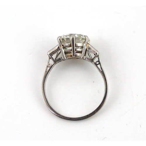 507 - A good platinum or white gold set single stone diamond ring, with two stone baguette cut diamond set... 