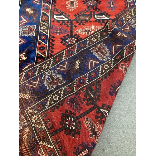 2102 - A Caucasian style red ground rug, 220cm x 140cm