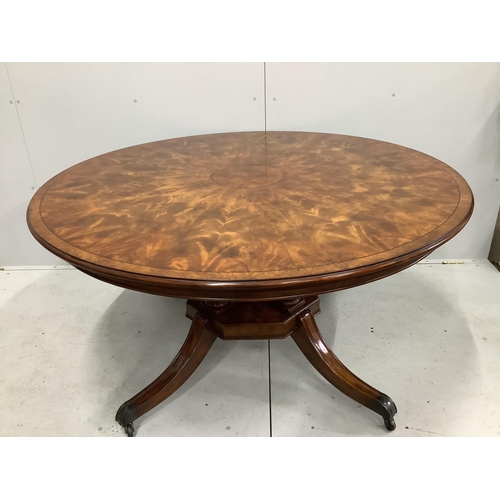 143 - A reproduction George III style circular mahogany extending dining table with detachable segmental o... 