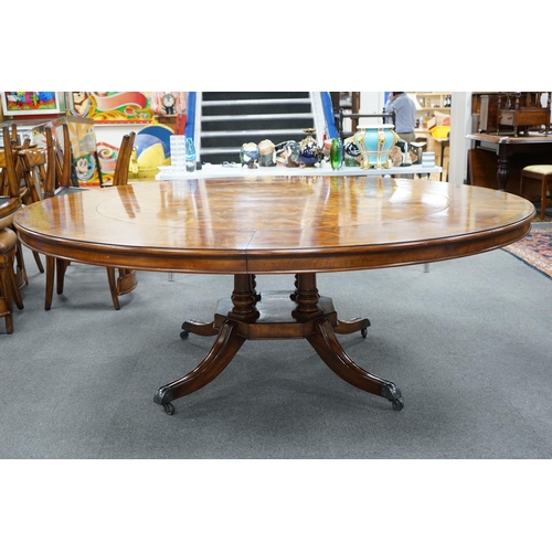 143 - A reproduction George III style circular mahogany extending dining table with detachable segmental o... 