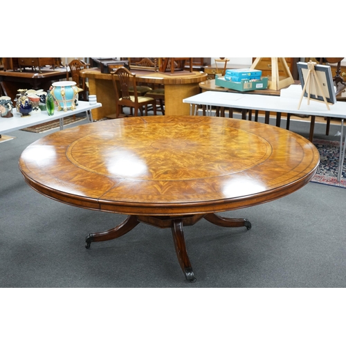 143 - A reproduction George III style circular mahogany extending dining table with detachable segmental o... 