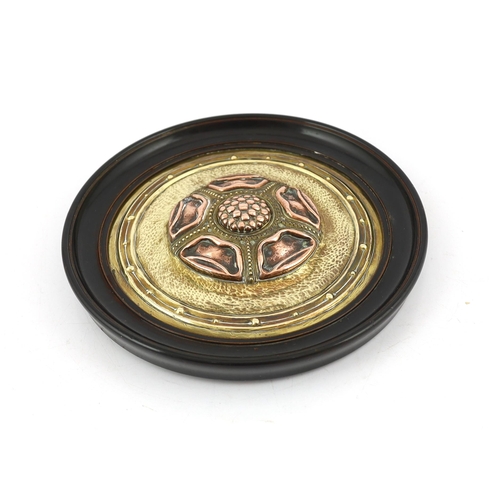 518 - An Arts and Crafts brass and copper roundel, in the manner of Archibald Knox, monogrammed CA, ebony ... 