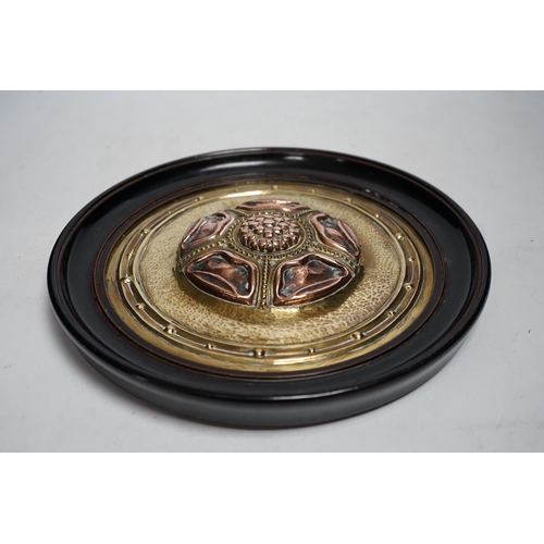 518 - An Arts and Crafts brass and copper roundel, in the manner of Archibald Knox, monogrammed CA, ebony ... 