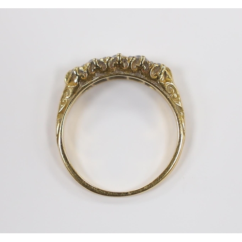 906 - An early 20th century yellow metal and graduated five stone diamond set half hoop ring, size I, gros... 